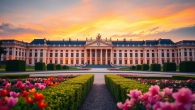 Visit the stunning Schönbrunn Palace in Vienna surrounded by intricate gardens at sunset.