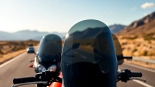 Explore high-quality motorcycle windshields reflecting sunlight against a scenic backdrop of open roads.