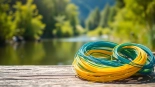 Experience the beauty of Fly fishing line coiled by a tranquil river surrounded by greenery.