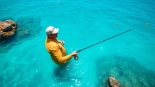 Angler engaged in saltwater fly fishing, showcasing vibrant ocean scenery and dynamic fishing action.